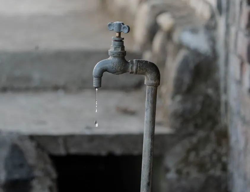 Close-up of a dripping faucet, a common sign of water pressure issues.
